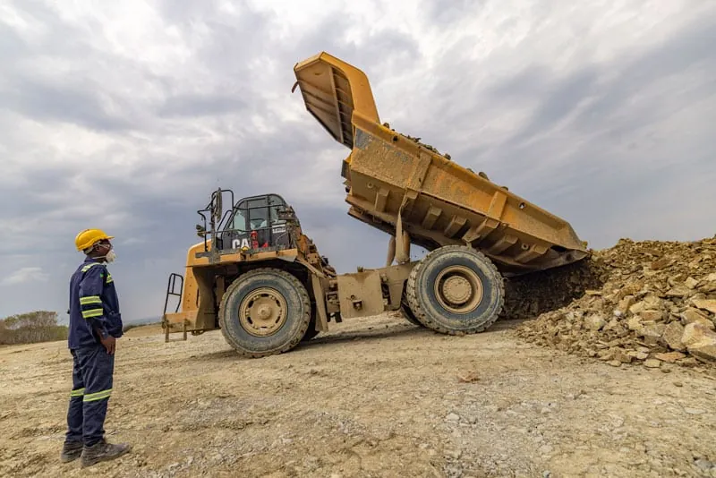 A truck tipping as a spotter watches